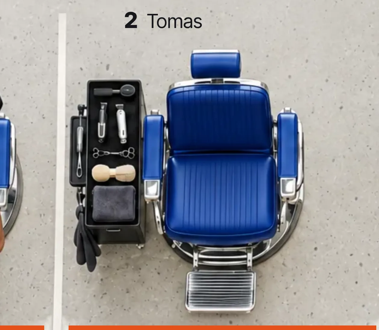 Overhead view of an empty blue barber chair in its bay beside a tool trolley, labelled chair 2, Tomas.